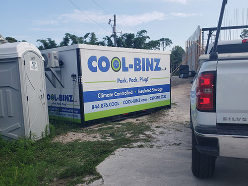 cool binz container sitting next to portable potty with white silverado truck parked nearby