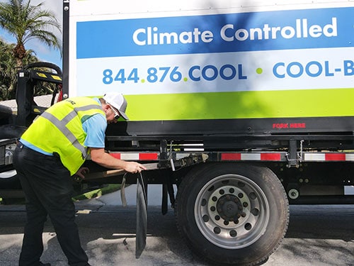 cropped image of employee unhitching cool binz container from company truck flatbed