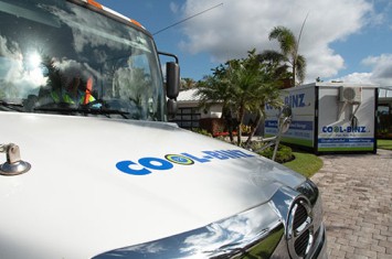 front hood of cool binz truck with employee sitting in driver's seat overlooking cool binz container in the distance