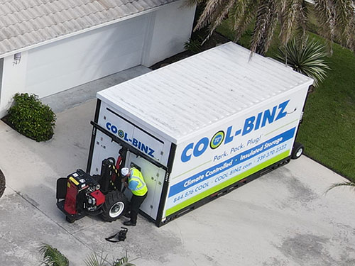 widely zoomed out image of non-climate controlled bin being unloaded on large residential driveway