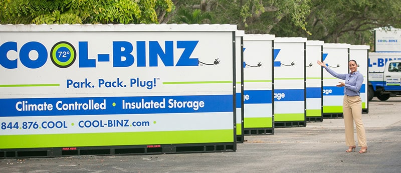 woman standing to the right pointing at rows of Cool-Binz climate controlled storage bins